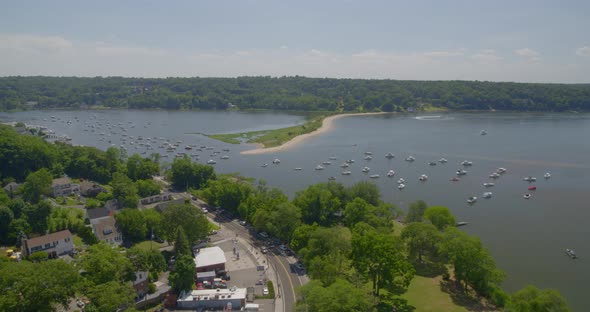 Rising Aerial View of Boats Anchored on Harbor Near a Thin Strip of Land