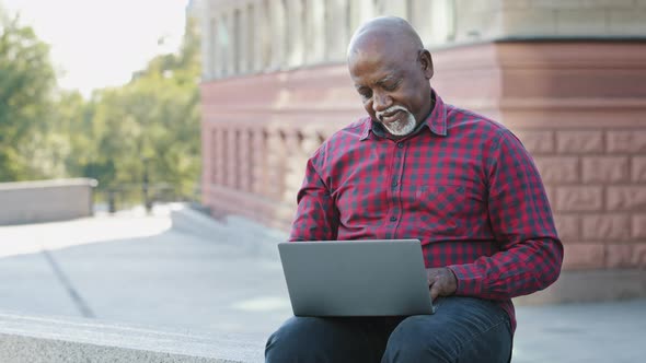 Happy Senior 60s Aged African American Customer Using Laptop Outdoors Shopping Online
