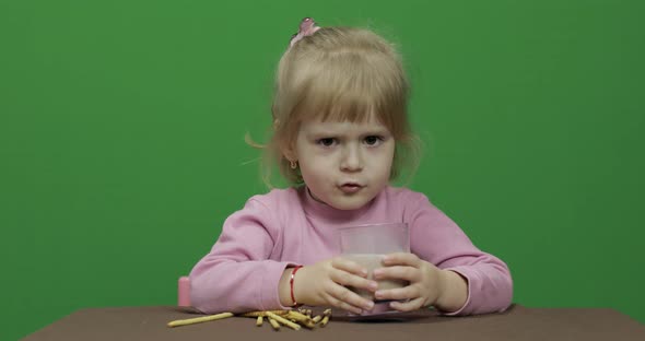 The Child Eats Cookies. A Little Girl Is Eating Cookies Sitting on the Table.