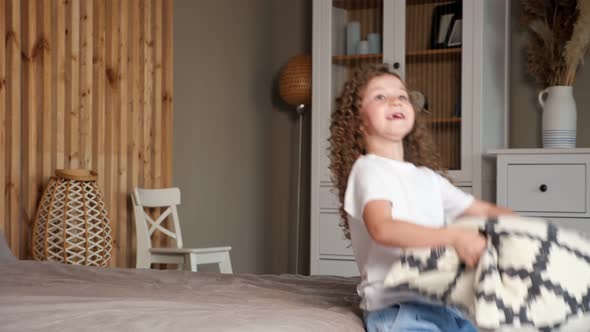 Delighted Young Preschooler Girl Falls on Large Grey Bed