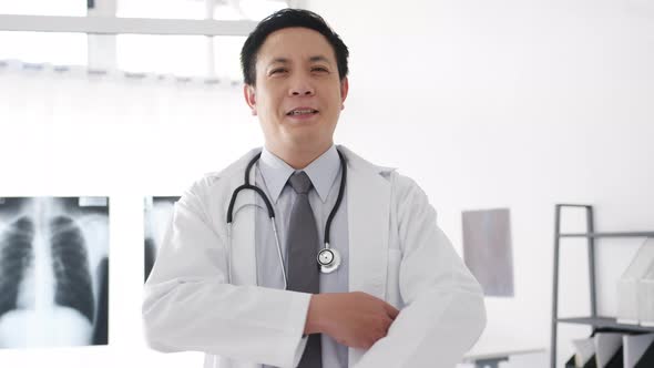 Young Asia male doctor looking at camera, smile and arms crossed while video conference.