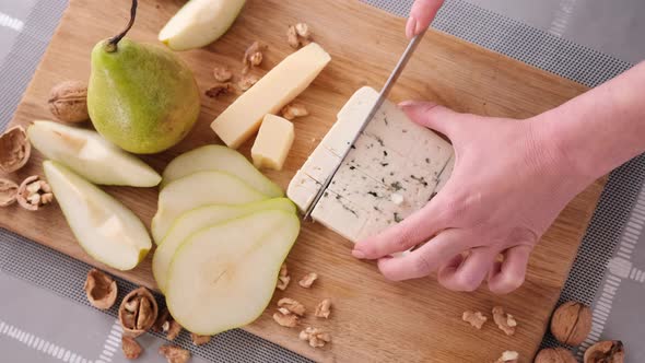 Making Pear and Blue Cheese Salad on  Slicing Cheese on a Wooden Board