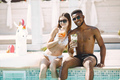 Caucasian girl and black boy sitting near the pool and drinking cocktails - PhotoDune Item for Sale