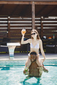Young girl and black male friend relaxing in a swimming pool and drinking a cocktails - PhotoDune Item for Sale