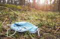 Close up picture of a discarded disposable medical face mask in the forest, selective focus. - PhotoDune Item for Sale