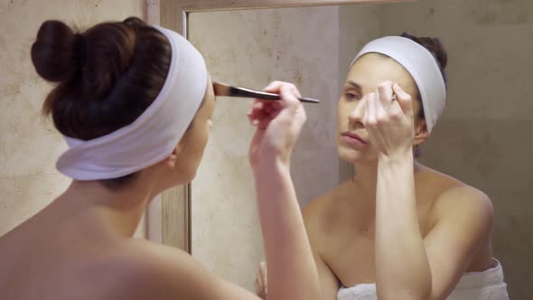 Beautiful Young Woman Applies Fluid Looking in the Mirror 