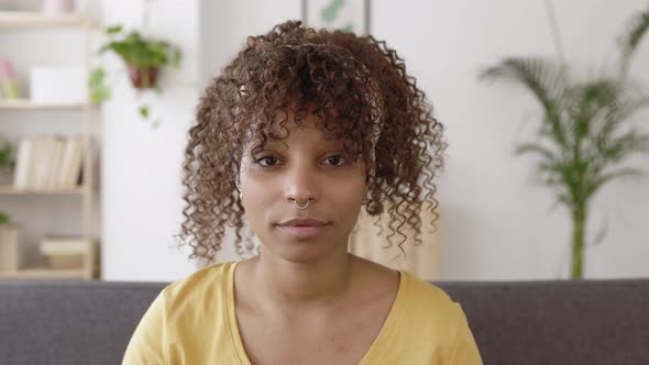 Young African American Woman Smiling at Camera While Sitting on Sofa at Home