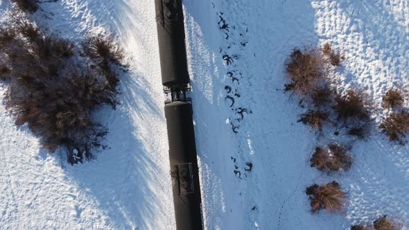 Train oil trailers trough a marsh in winter snow followed