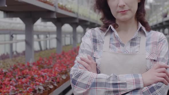 Unrecognizable Mid-adult Caucasian Woman in Apron Crossing Hands and Smiling. Positive Female