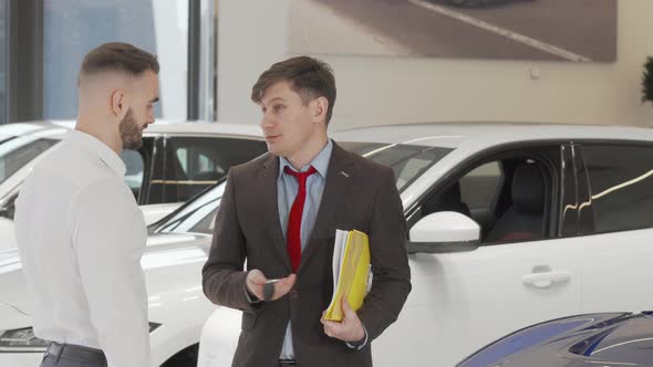 Cheerful Car Dealer Shaking Hands with a Customer After Giving Him Car Keys