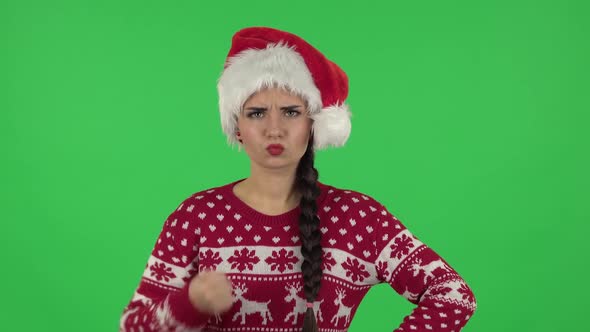 Sweety Girl in Santa Claus Hat Threatens with a Fist. Green Screen