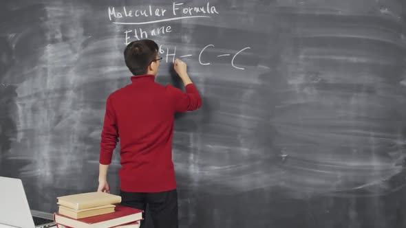 Chemist Writing Formula on Blackboard