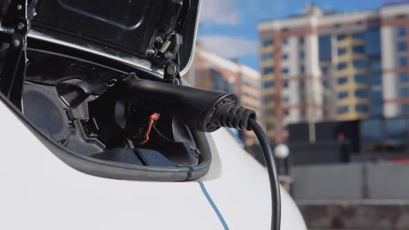 Electric Car Charging Batteries with Electricity Through Power Cable on Parking Lot in a Residential