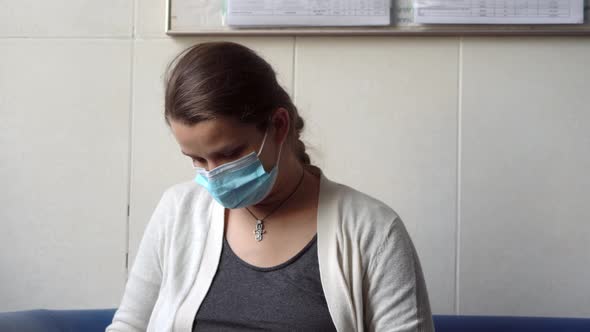 Young Pregnant Woman In Medicine Protective Mask Reading On Couch Waiting For Appointment Medical