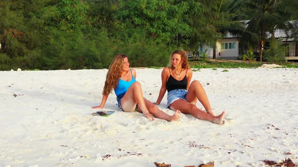 Sexy smiling ladies travelling spending quality time on beach on summer white sandy and blue 4K back