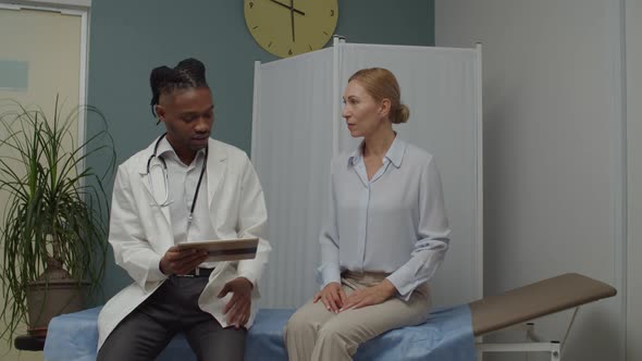 Physician Using Tablet Explaining Test Results to Mature Woman Indoors