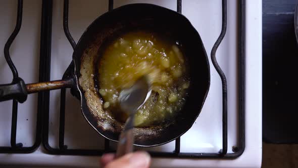 Chef making homemade caramel sauce, mixing butter and sugar over hot stove