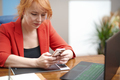 Redhead businesswoman using laptop and smartphone at the office - PhotoDune Item for Sale