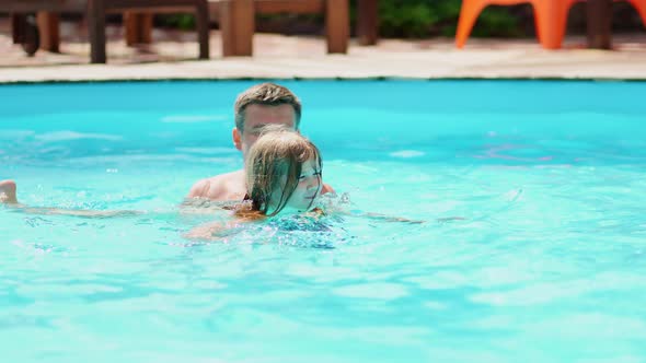 Dad Teaches His Daughter to Swim in the Pool