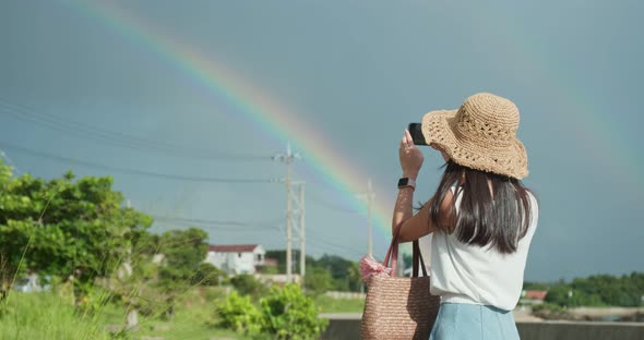 Woman taking photo on the raibow with blue sky