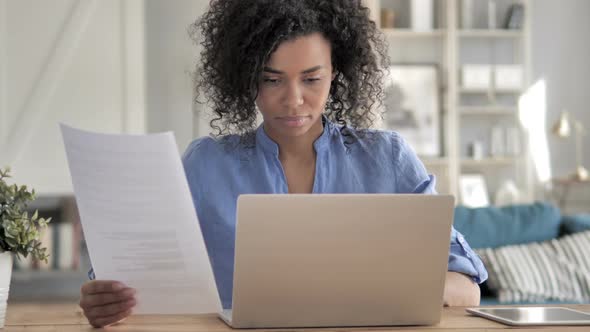 African Woman Working on Documents and Laptop