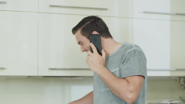 Closeup Smiling Man Talking Mobile Phone at Home Kitchen.