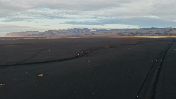 Drone Towards Mountains Over Black Sand