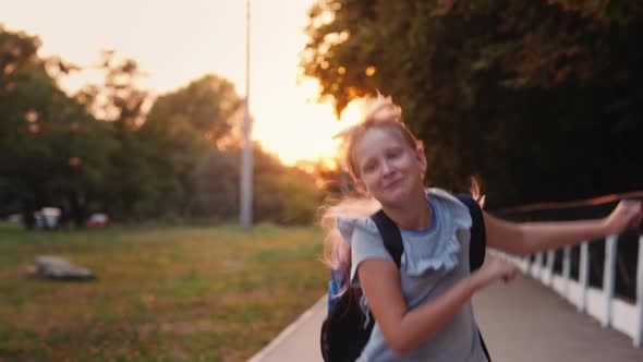 Cheerful Child with a Satchel Behind His Back Runs Towards the Camera