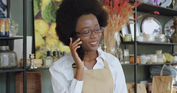 Woman with African Hairstyle which Talking on Smartphone while Working in Handmade Gift Shop