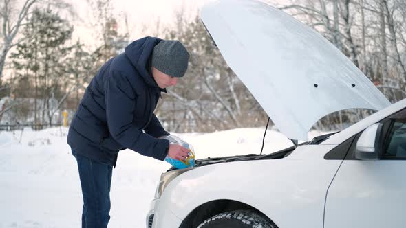 Man Pouring Washer Fluid in Tank of Car in Winter