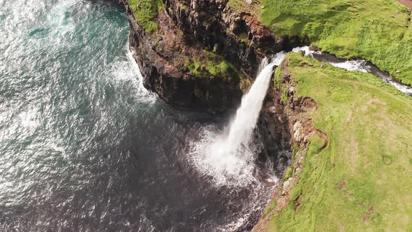 Stunning Waterfall Splashing From Cliff Aerial View. Mulafossur Waterfall Near Gasadalur Village at