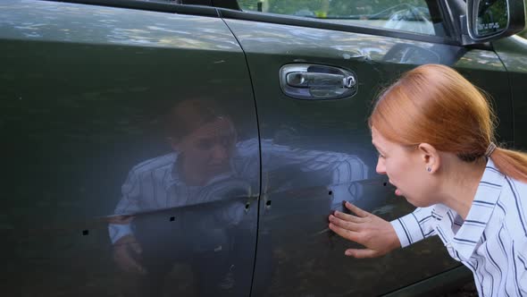 Young Woman Driver Looking at Scratch Damage of Her Car. Sad Person After Traffic Accident Crash