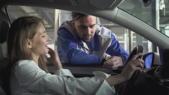 Young Woman Sitting in a Beautiful Car, and the Automaster at the Window Tells About the Technical