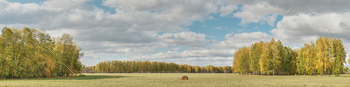 st, fields and one roll of hay against backdrop of cloudy sky on autumn day. Panorama