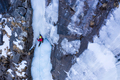 Woman is Placing an Ice Screw. Ice Climbing on Frozen Waterfall, Aerial View. - PhotoDune Item for Sale