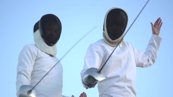 A man and woman fencing on the beach