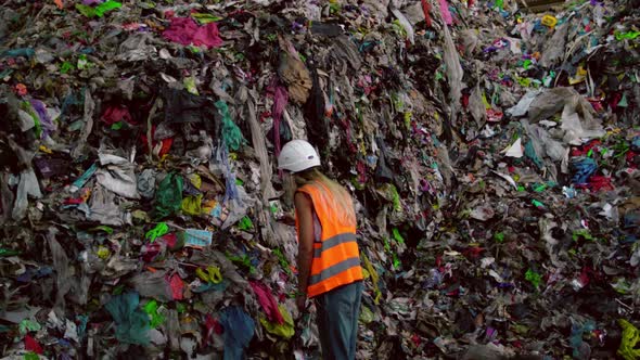 Young Female Blogger in Protective Gear Live Streaming at City Trash Dump Via Mobile Phone