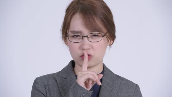 Face of Young Asian Businesswoman with Finger on Lips