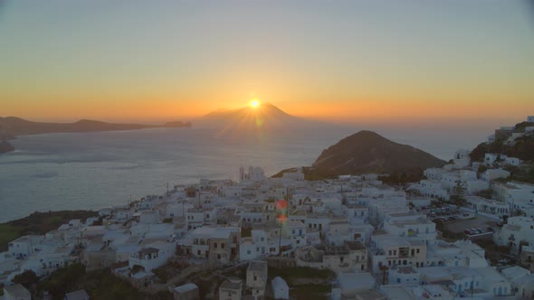 Aerial View of White Houses in Plaka Village and Sun Setting Behind Mountain
