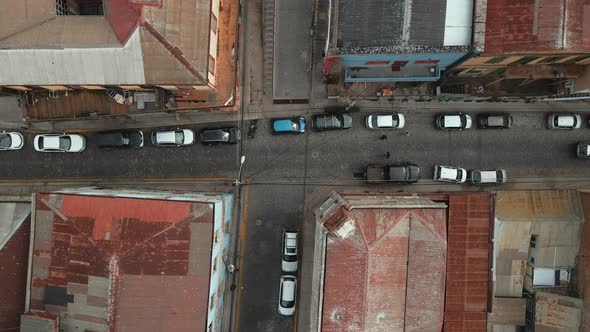 Aerial top down of cars parked inline in narrow street and houses with red rooftops in Valparaiso ci