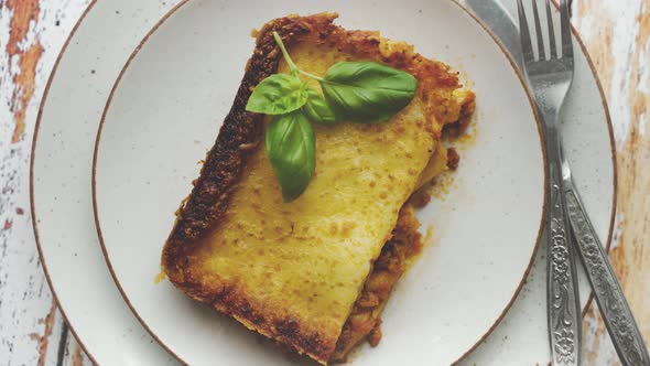 Homemade Tasty Meat Lasagna with Fresh Basil and Parmesan Cheese in a Plate on Wooden Background