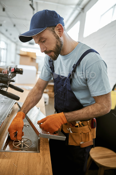 Repairman fixing professional coffee machine in cafe