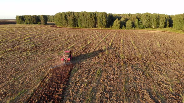 Red tractor loosens the soil