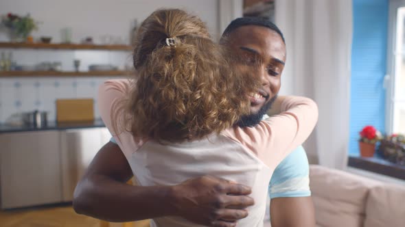 Smiling Loving Multiethnic Couple at Home Hugging Having Fun.