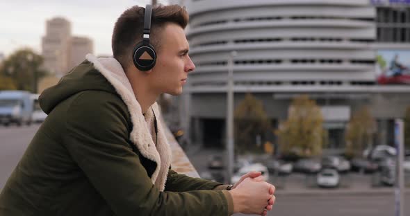 Young Man Listening To Music with Headphones in City and Thinking