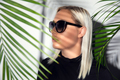 Profile of beautiful woman with sunglasses hiding behind tropical palm leaves - PhotoDune Item for Sale