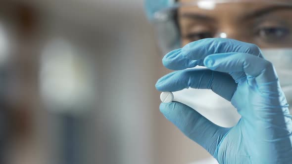 Pharmaceutical company researcher checking pills for required labeling, close-up