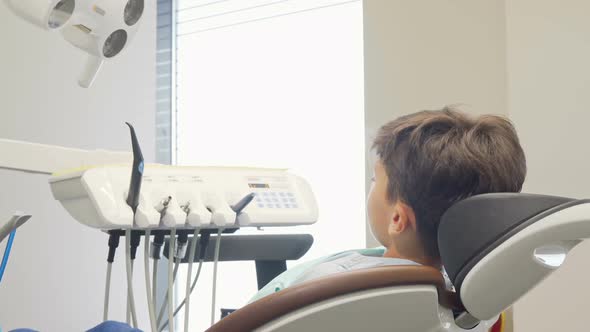 Charming Young Boy Smiling To the Camera, Sitting in Dental Chair
