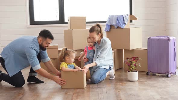 Caucasian Family Man Woman and Two Girls Play with Moving Box