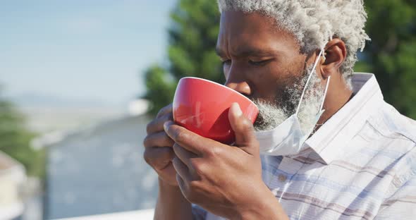 Senior man with face mask on his chin drinking coffee